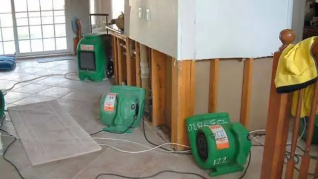 Wall cavities opened up with air movers drying the room after a leak